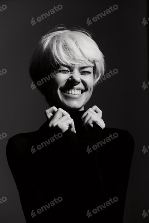 Preview: Joyful young woman with short blonde hair expressing happiness in a black turtleneck, captured in a