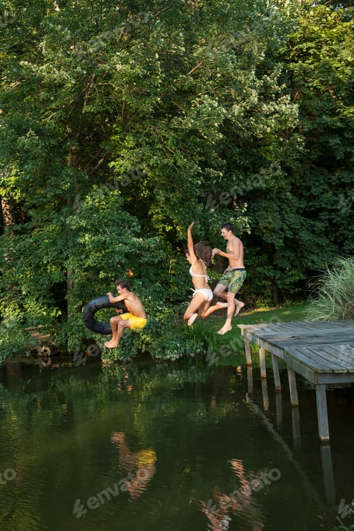 Preview: Three young boys jumping from the jetty into a still pool of water.