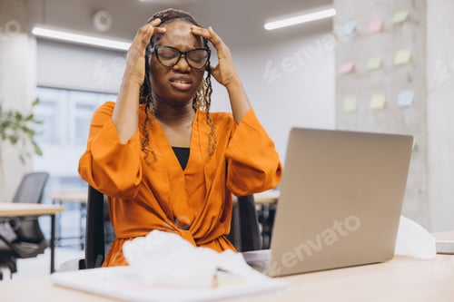 Preview: African american businesswoman experiencing stress while working on a laptop in a modern office