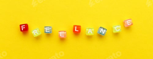 Preview: word freelance made from multicolored plastic cubes of beads on yellow background. banner