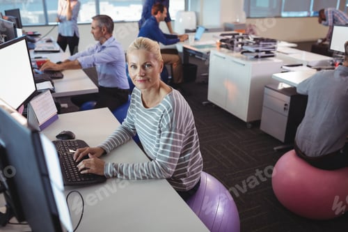 Preview: Portrait of businesswoman working at desk while sitting on exercise ball