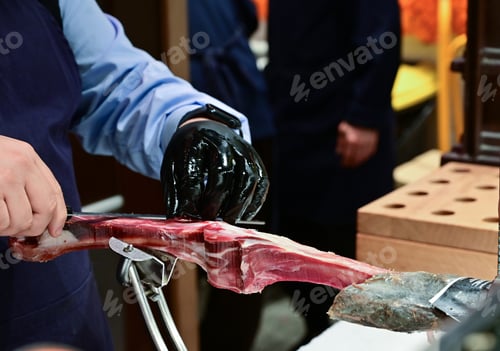 Preview: Man Slicing Spanish Jamon with Knife