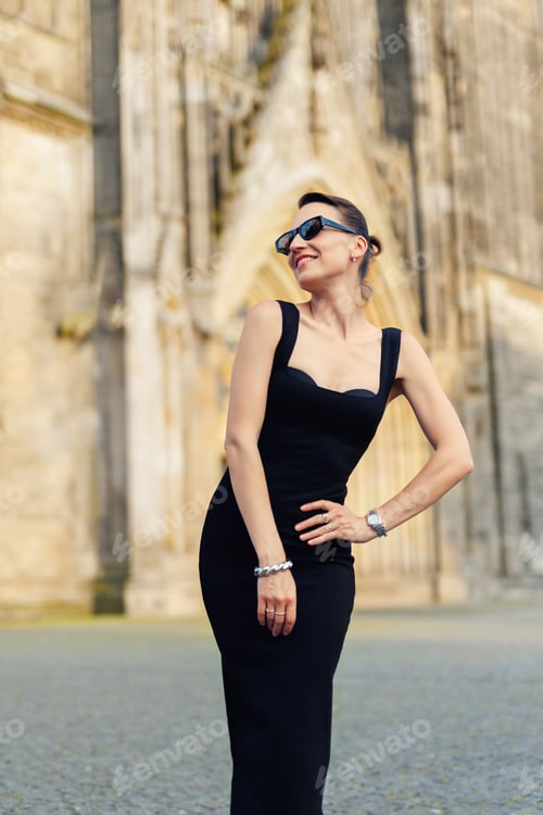 Preview: Portrait young adult elegant woman black dress and sunglasses smiles confidently