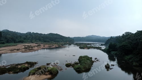 Preview: Serene river landscape with green vegetation and hills.