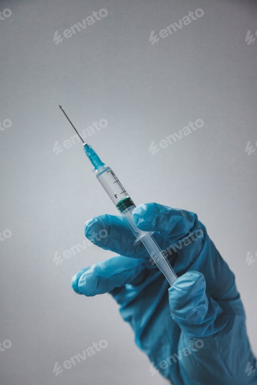 Preview: Hand in blue medical gloves holding syringe with an injection. Concept of medical procedures