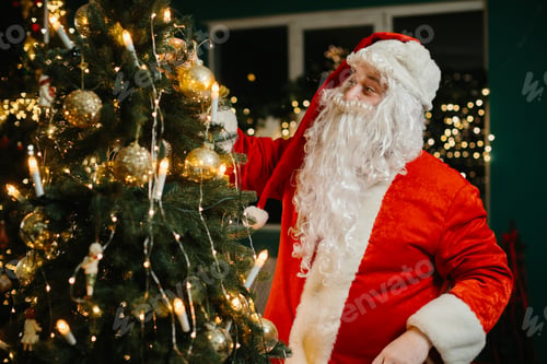 Preview: Santa claus decorating christmas tree with golden ornaments and lights
