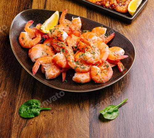 Preview: Shrimp dish served with lemon and garnished with herbs in a rustic setting