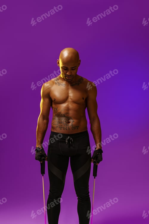 Preview: Sporty man performs exercises with expander on studio background. Strength and motivation