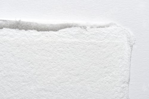 Preview: Close-up of textured white paper edge with subtle shadow on light background