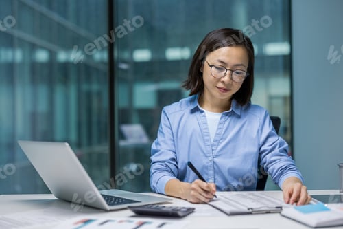 Preview: Asian woman working in office with laptop and documents