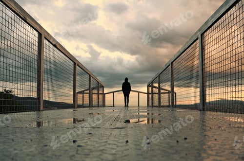 Preview: Lonely person standing on a bridge and enjoying the beautiful view of the sunset over a cityscape