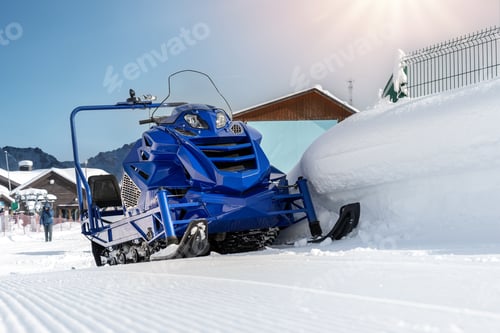 Preview: Front view big modern snow mobile scooter atv alpine mountain reosrt against sunny sky on cold snowy