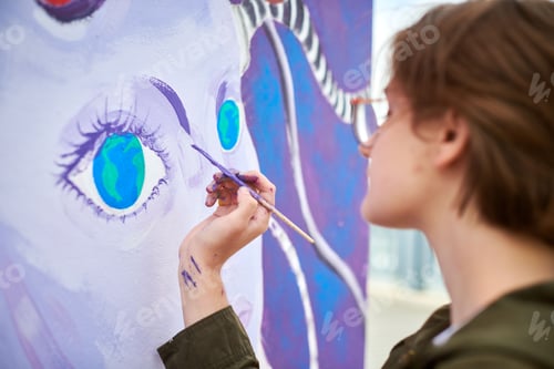 Preview: Female painter draws picture with paintbrush on canvas for outdoor street exhibition
