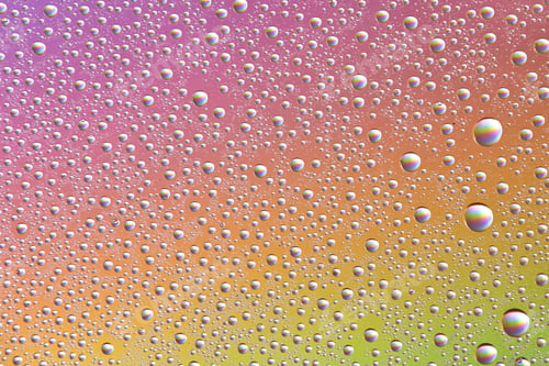 Preview: Drops on glass of different sizes and colors on a colored background, texture