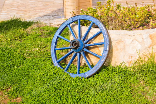 Preview: Concept of decor for garden - wooden wheel on a background of green grass