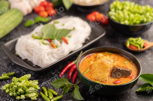 Preview: Chicken curry in a black cup with rice noodles.
