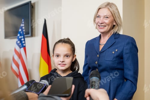 Preview: Schoolgirl and mature blond female answering questions of journalists