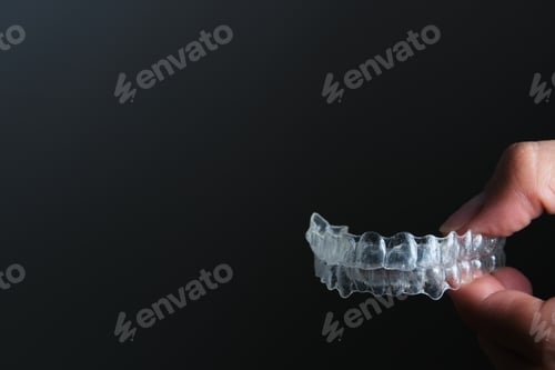Preview: hand holding transparent dental retainers