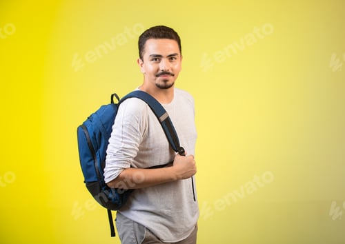 Preview: Man holding a blue backpack and looking straight while smiling