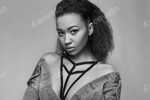 Preview: Portrait Of Glamor Elegant Black Woman Model In Jeans Jacket Posing On A Gray Background In Studio