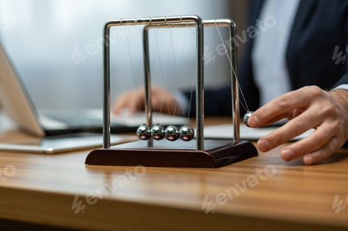 Preview: Senior executive engaging with newton's cradle on office desk in a corporate environment