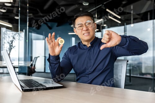 Preview: Dissatisfied asian businessman holding finger down, bad losing gesture, holding virtual currency