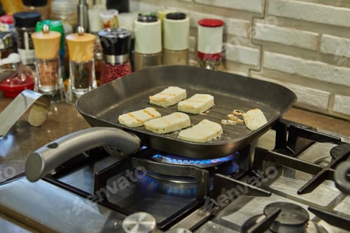 Preview: Halloumi cheese is fried on ribbed pan over fire on gas stove
