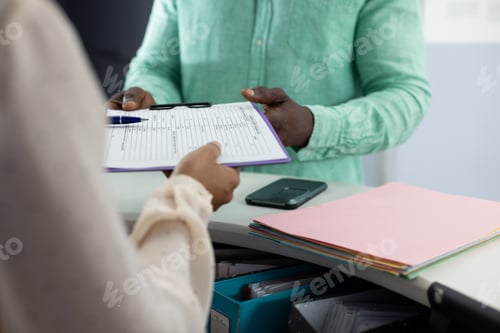 Preview: Midsection of biracial medical receptionist handing documents to african american patient