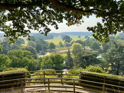 Preview: Scenic park view with wooden railing and lush greenery.
