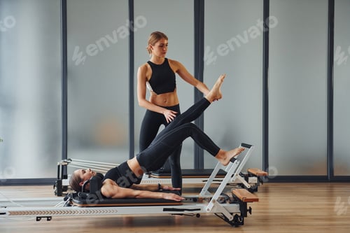 Preview: Two women in sportive wear and with slim bodies have fitness yoga day indoors together
