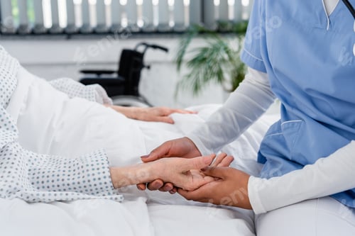 Preview: Cropped view of african american nurse checking pulse on hand of senior patient