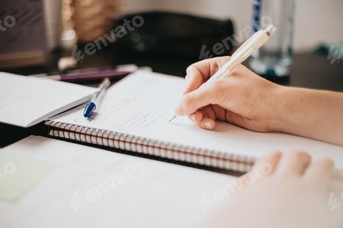 Preview: Closeup image of a woman hand writing on a notebook, doing homework during university