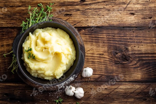 Preview: Mashed potatoes, boiled puree in cast iron pot on dark wooden rustic background, top view
