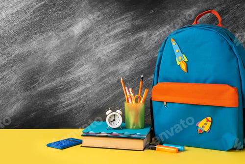 Preview: School backpack with colorful school supplies on the background of black chalkboard.
