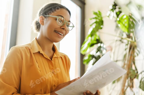 Preview: African American business woman, freelancer wearing eyeglasses holding documents