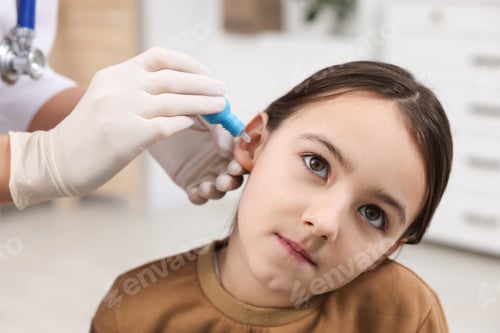 Preview: Doctor applying medical drops into girl's ear indoors