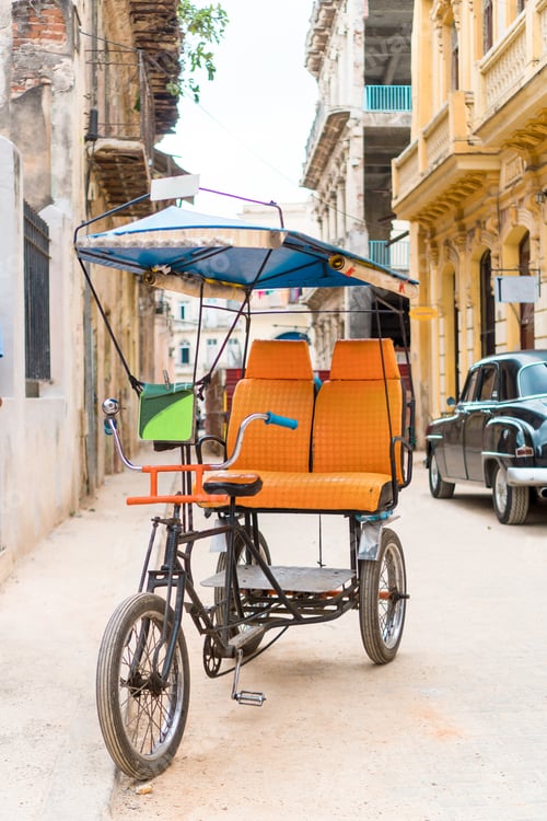 Preview: Cuban taxi bicycle parked in front of colorful colonial houses