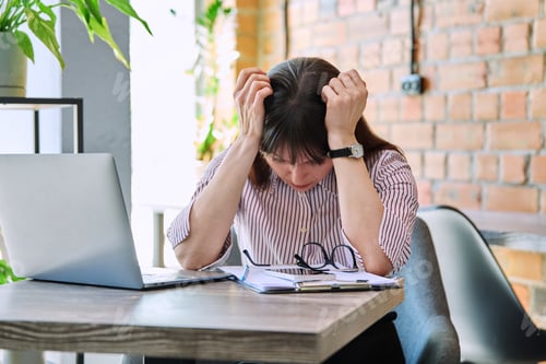 Preview: Mature tired worried tense woman at workplace experiencing stress headache