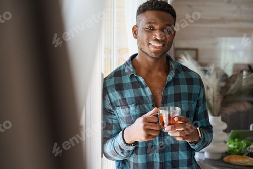 Preview: African American man stands by window with cup of tea