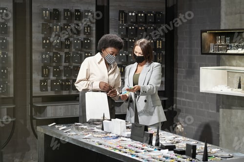 Preview: Young shop assistant helping African female customer
