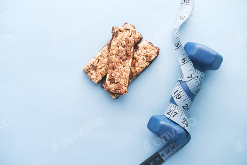 Preview: dumbbell, measurement tape and oat protein bars on table