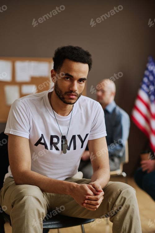 Preview: Young unhappy man with post traumatic syndrome sitting against counselor