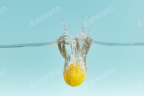 Preview: fresh lemon falling deep in water with splash on blue background