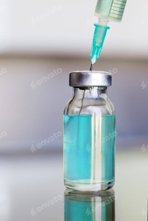 Preview: Vial filled with liquid vaccine in medical lab with syringe.
