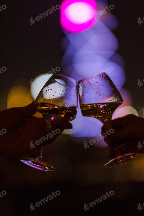 Preview: Two people cheering with glasses at night