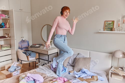 Preview: Indoor shot of joyful redhead woman dances to music enjoys favorite music dressed in casual clothes