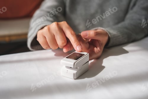 Preview: A woman using digital fingertip pulse oximeter device to measure oxygen and blood pulse rate