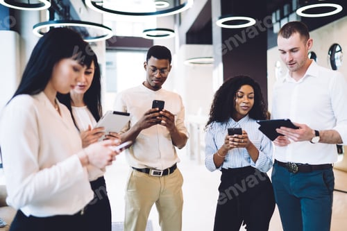 Preview: Positive multiethnic coworkers using gadgets and standing together in office