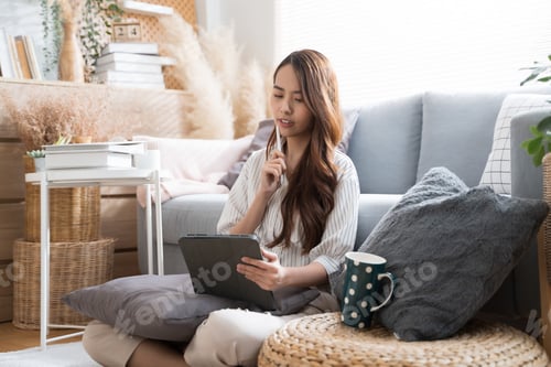 Preview: Young Asian woman using tablet and pen in living room