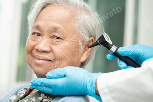 Preview: Audiologist or ENT doctor use otoscope checking ear of asian senior woman patient treating